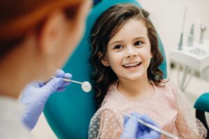 Lachendes Kind auf Zahnarztstuhl, Ärztin mit Werkzeug